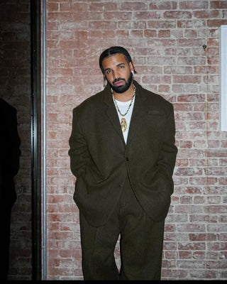 Man wearing a brown suit standing against a brick wall
