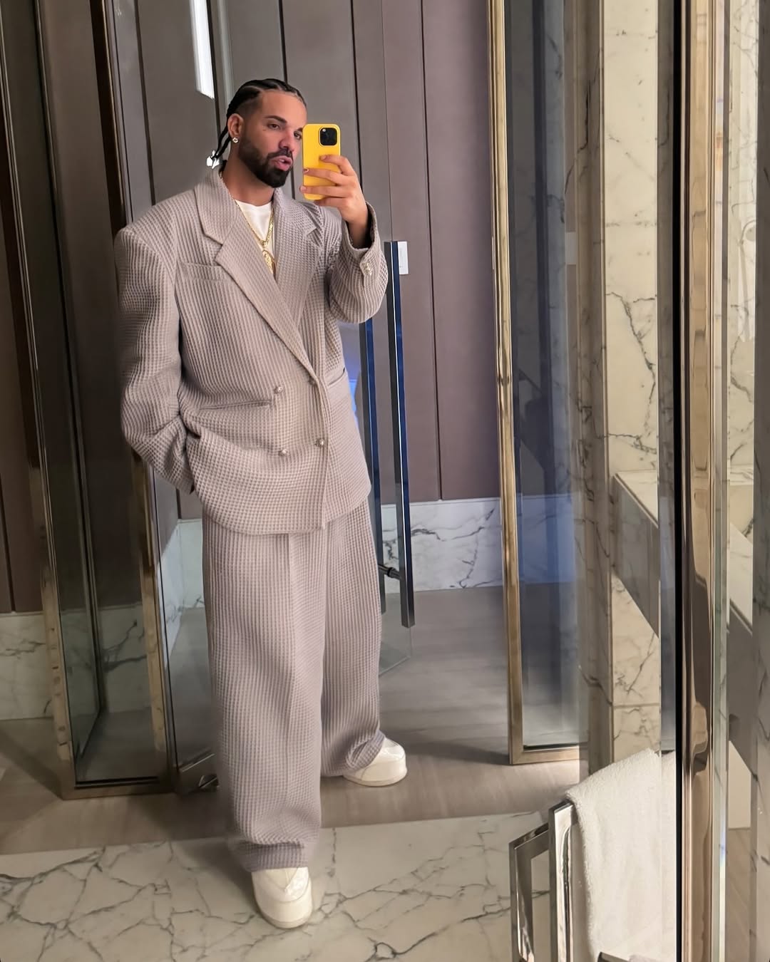 Person wearing a gray suit taking a mirror selfie in an indoor setting.