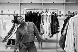 Woman standing in a clothing store with racks of clothes and shoes in the background