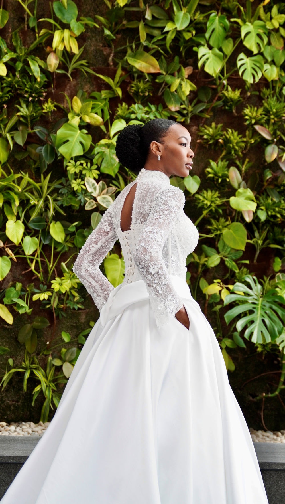 Woman in a white wedding dress standing in front of green foliage