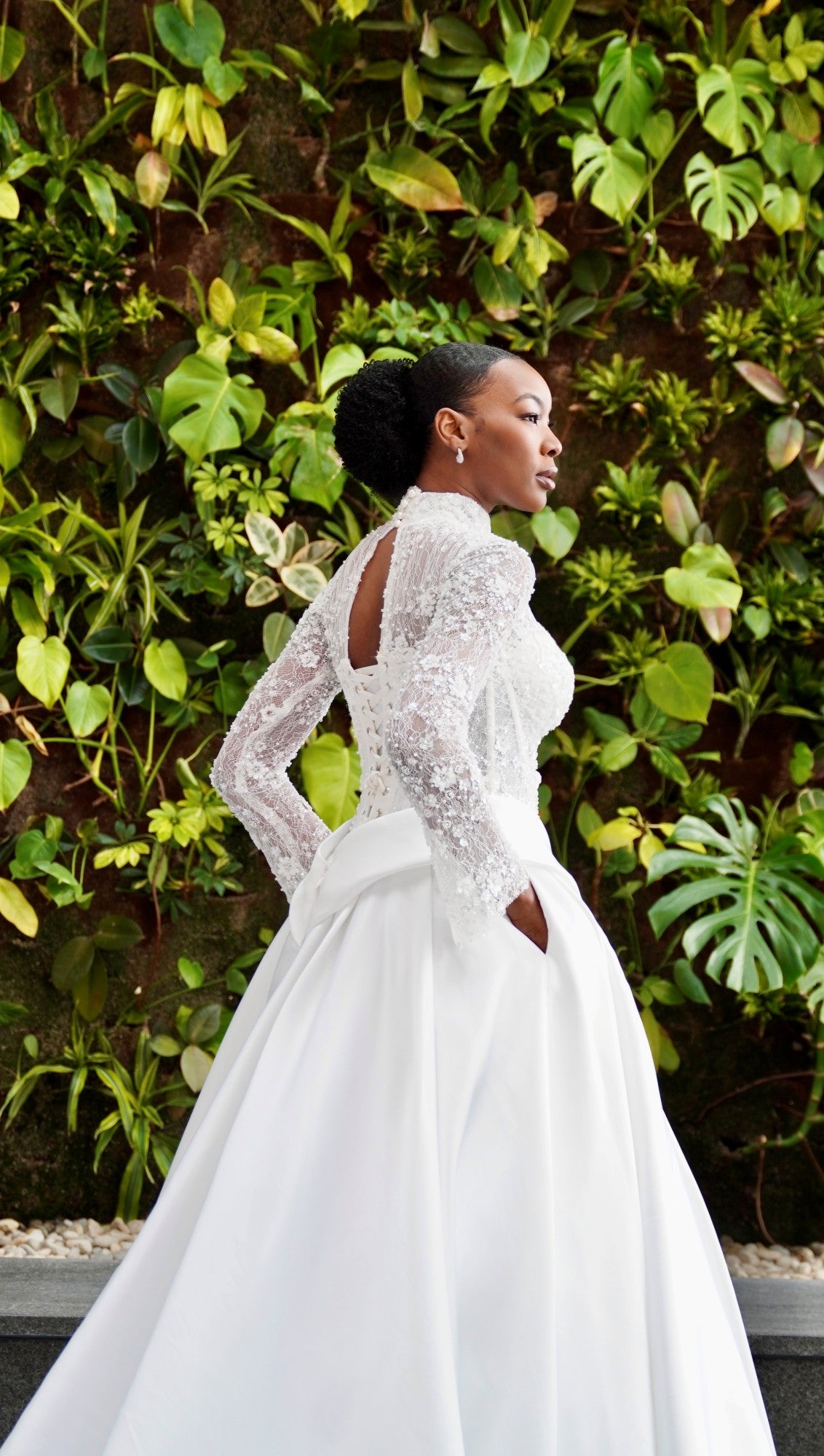 Woman in a white wedding dress standing in front of green foliage