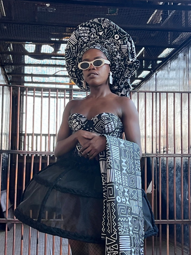 Designer Zoba Martin in an African traditional formal dress by herself: a black and white print corset, matching headwrap and sheer skirt.