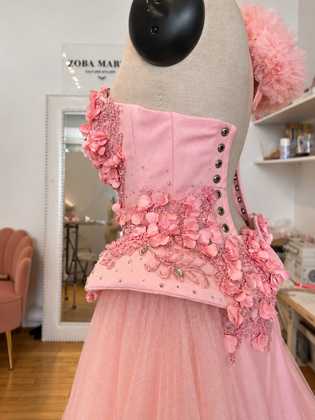 Side view of a pink floral Zoba Martin couture dress with 3D petals and a tulle skirt in the atelier studio.