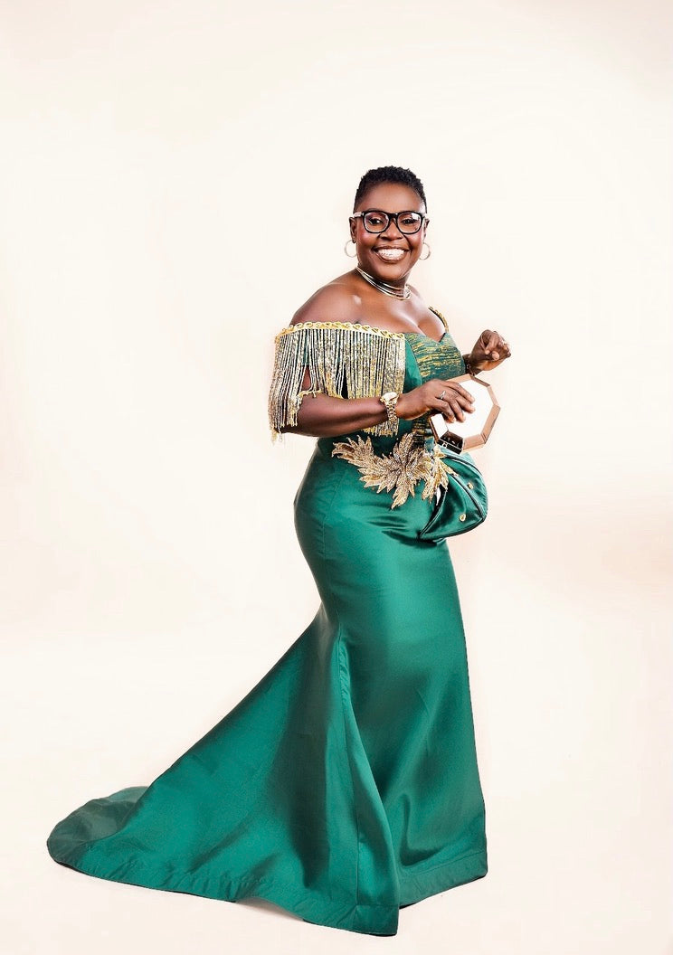 Full-length view of Zoba Martin's mom in an emerald gold Zoba Martin mermaid gown with gold fringe sleeves for her 50th celebration.
